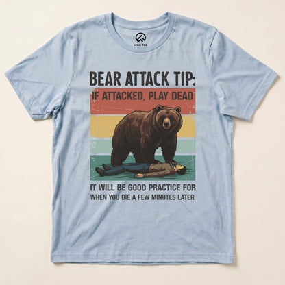 A light blue graphic t-shirt featuring a playful design of a bear and a person, labeled "Bear Attack Tip Retro Shirt.