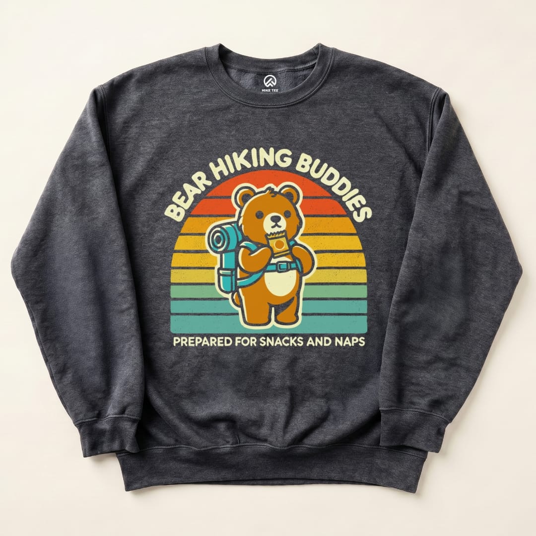 A dark sweatshirt featuring the "Bear Hiking Buddies Sweatshirt" graphic of a bear with a backpack, accompanied by the slogan "Prepared for Snacks and Naps.