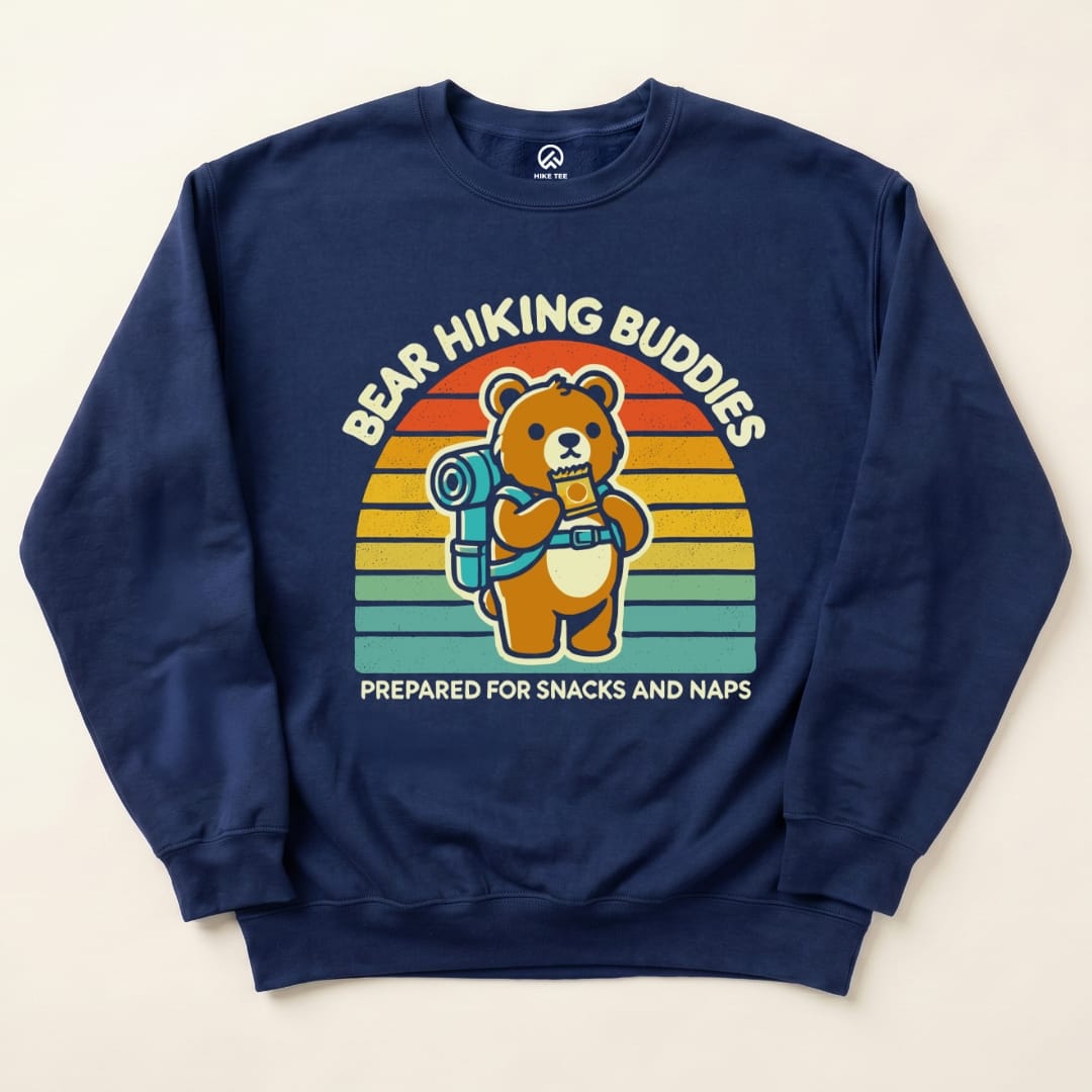 The navy "Bear Hiking Buddies Sweatshirt" features a cartoon bear with a backpack and snacks, surrounded by a colorful sunset design.