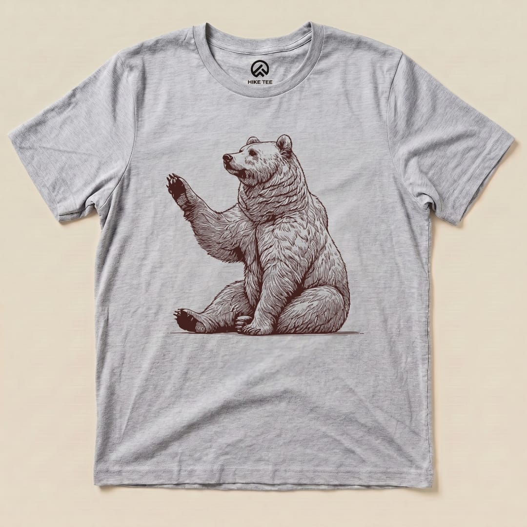 A light gray graphic t-shirt featuring a seated bear with a raised paw, titled "Bear is Watching Shirt.