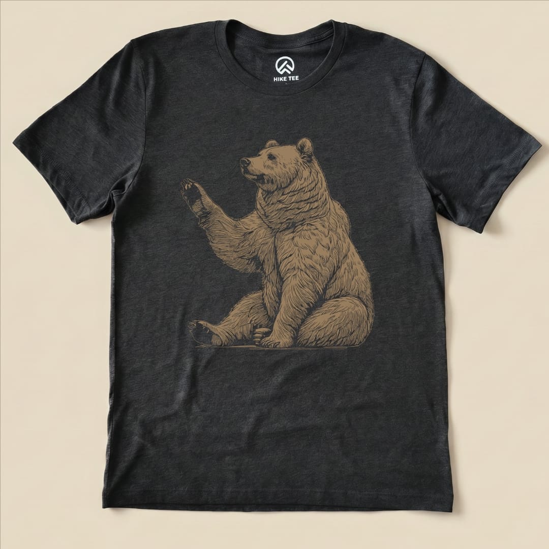 A graphic t-shirt featuring a sitting bear with a raised paw, titled "Bear Is Watching Shirt," displayed flat.