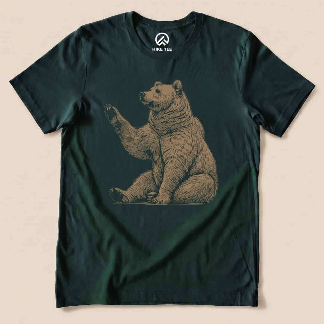 A graphic t-shirt featuring a bear in a sitting position, shown with the text "Bear Is Watching Shirt" in a playful design.