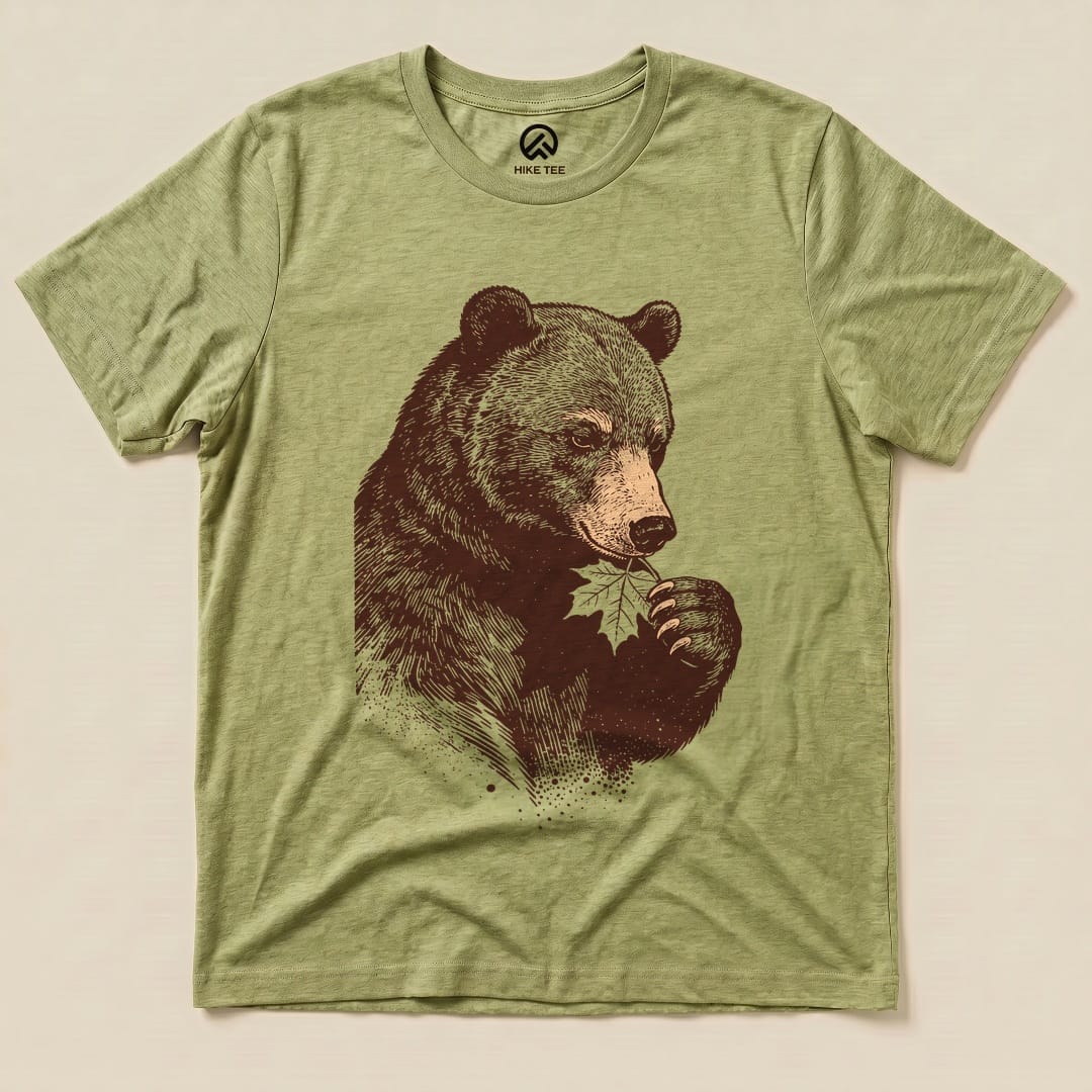 The Bear With Leaf Shirt features a detailed graphic of a bear holding a leaf, printed on a soft, olive green graphic t-shirt.