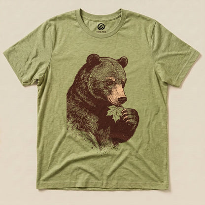 The Bear With Leaf Shirt features a detailed graphic of a bear holding a leaf, printed on a soft, olive green graphic t-shirt.