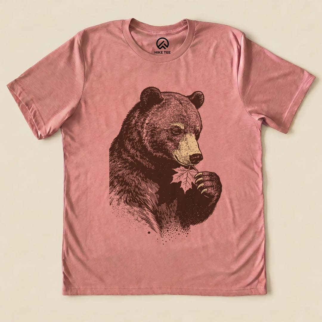 The graphic t-shirt features a bear holding a leaf, displayed on a pink background, labeled as the "Bear With Leaf Shirt".