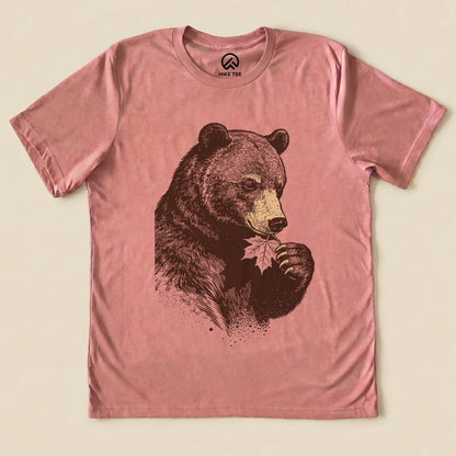 The graphic t-shirt features a bear holding a leaf, displayed on a pink background, labeled as the "Bear With Leaf Shirt".