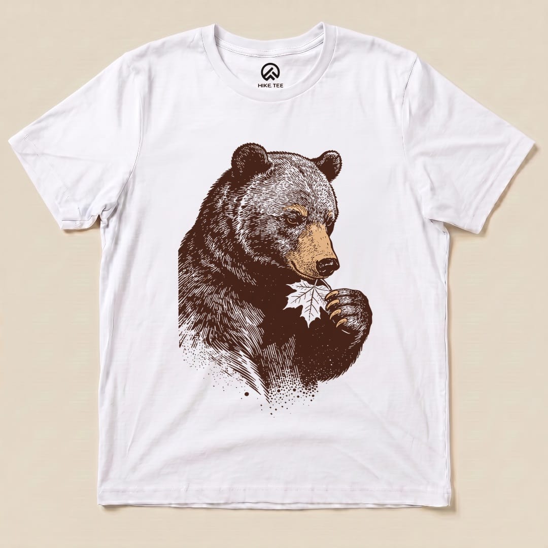 A graphic t-shirt features a detailed illustration of a bear holding a leaf, titled the "Bear With Leaf Shirt," on a white background.