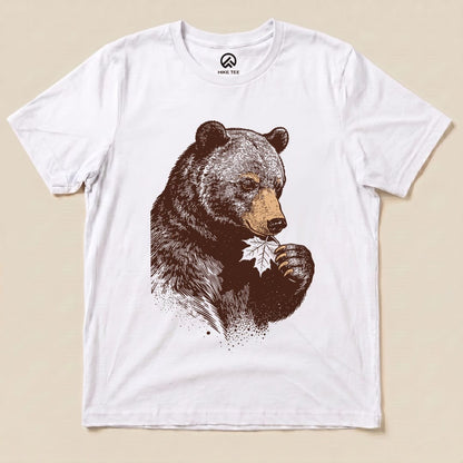 A graphic t-shirt features a detailed illustration of a bear holding a leaf, titled the "Bear With Leaf Shirt," on a white background.