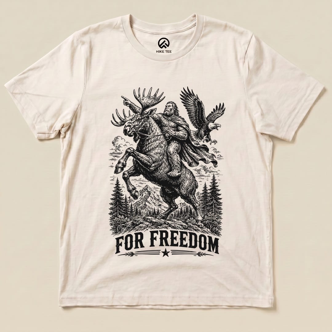The graphic t-shirt features a bold print of Bigfoot riding a moose with an eagle overhead and the phrase "FOR FREEDOM.