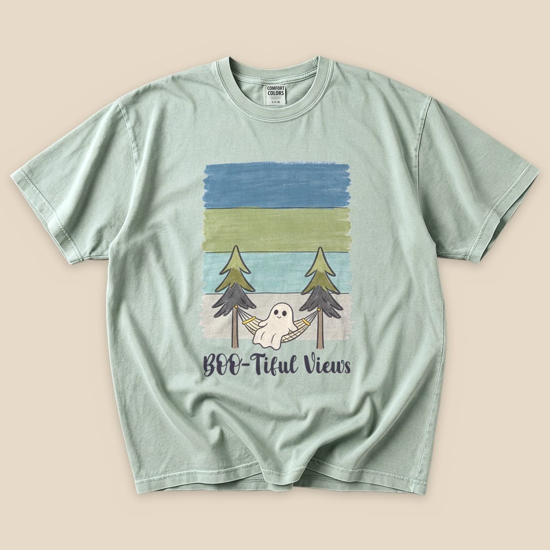 A graphic t-shirt featuring a ghost in a hammock between trees, with "Boo-tiful Views" printed below in playful lettering.