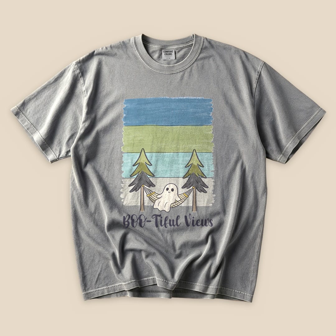A gray graphic t-shirt featuring a playful design with a ghost in a hammock surrounded by trees and the text "Boo-tiful Views".