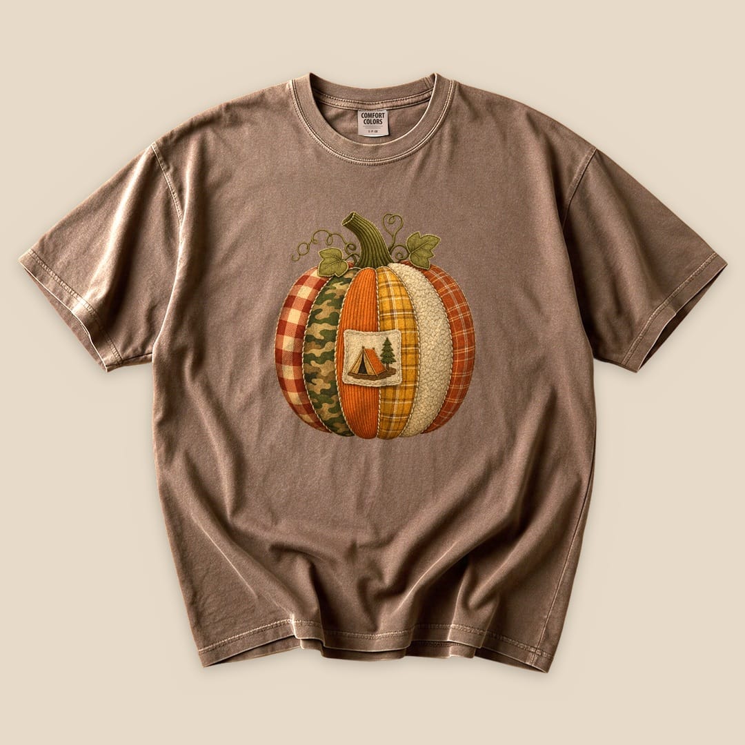 The Camp Pumpkin T-Shirt features a whimsical graphic of a patchwork pumpkin with a camping tent and tree design.