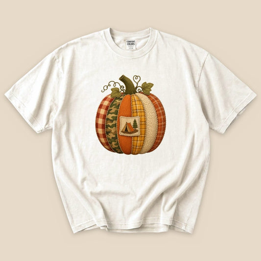 A Camp Pumpkin T-Shirt in cream features a colorful pumpkin design made of various fabrics and a small camping emblem.