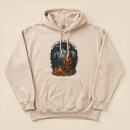 The Campfire Sergeant Bear Hoodie features a bear relaxing by a campfire, surrounded by trees, with a humorous slogan above.