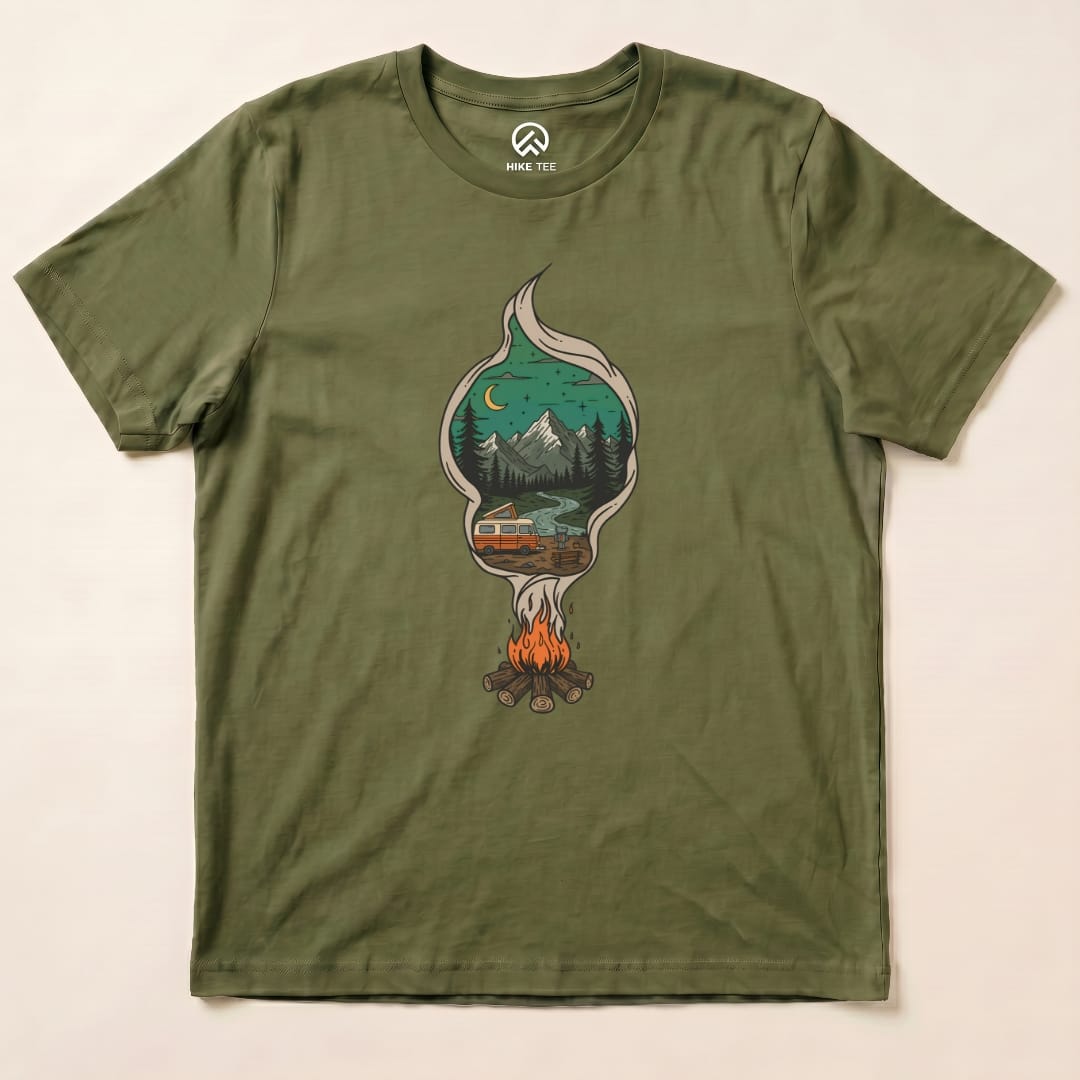 The Campfire Smoke Shirt features a graphic of a campfire surrounded by mountains and a cabin, printed on an olive green t-shirt.