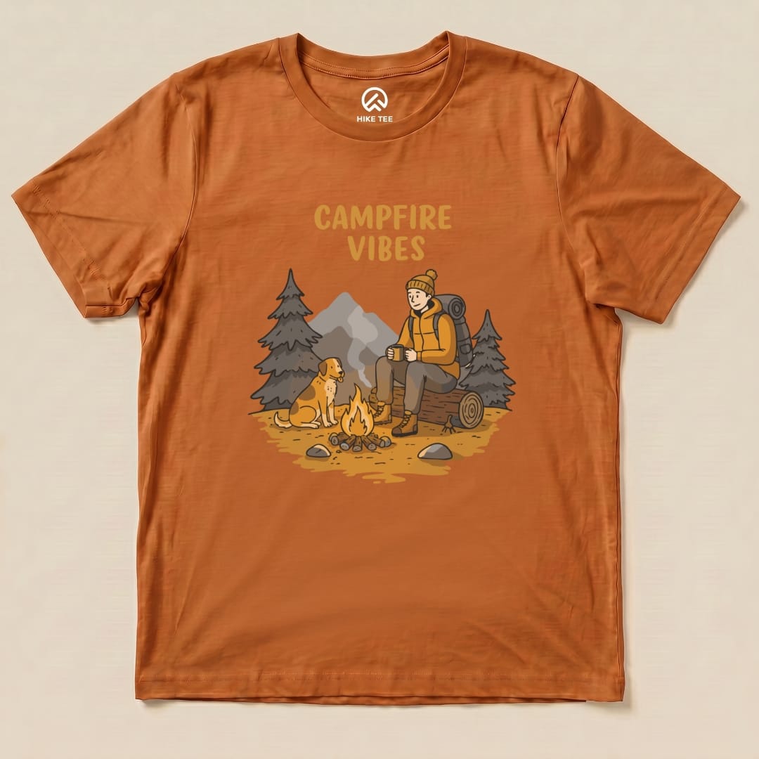 The Campfire Vibes Shirt features a graphic of a hiker sitting by a campfire with a dog, surrounded by trees and mountains.