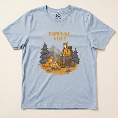 A light blue graphic t-shirt featuring the phrase "CAMPFIRE VIBES" and an illustration of a hiker sitting by a campfire with a dog.