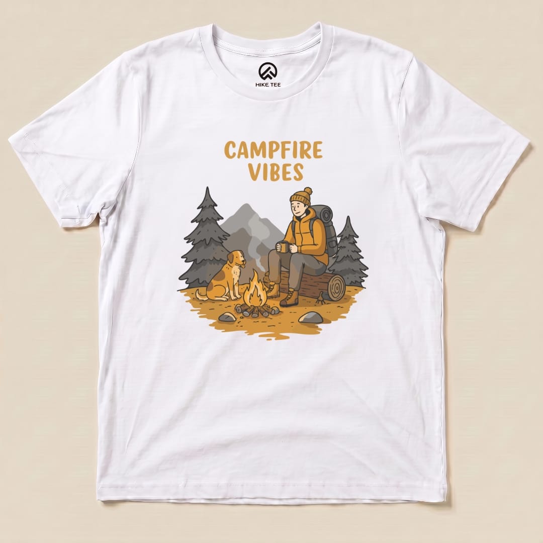 A graphic t-shirt featuring a cozy campfire scene, with the words "CAMPFIRE VIBES" above an illustrated hiker and dog.