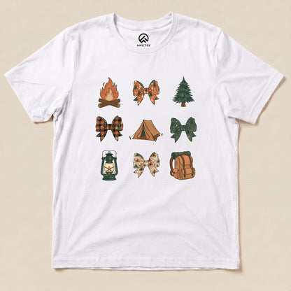 The Camping Bows Shirt features a white graphic t-shirt adorned with various camp-themed bows, a campfire, lantern, tent, and tree designs.