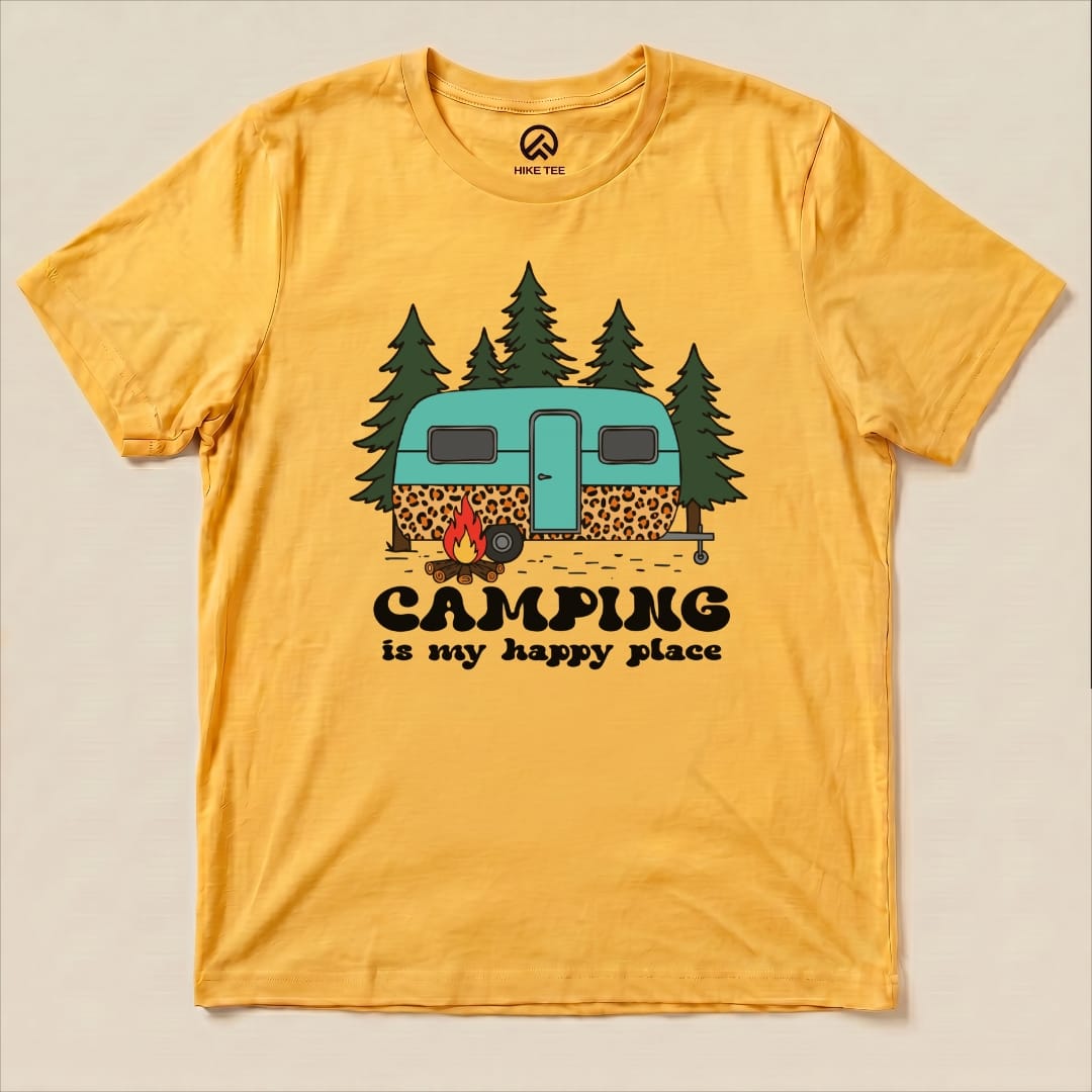 A yellow graphic t-shirt featuring a colorful print of a camper, trees, and the slogan "Camping is my happy place.