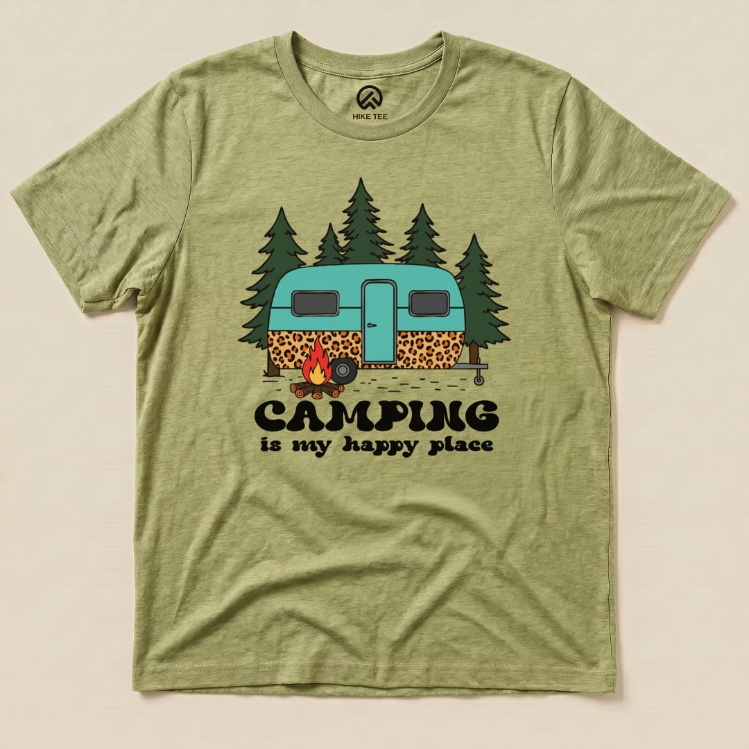 A green graphic t-shirt featuring a vintage camper, trees, and the slogan "Camping is my happy place.