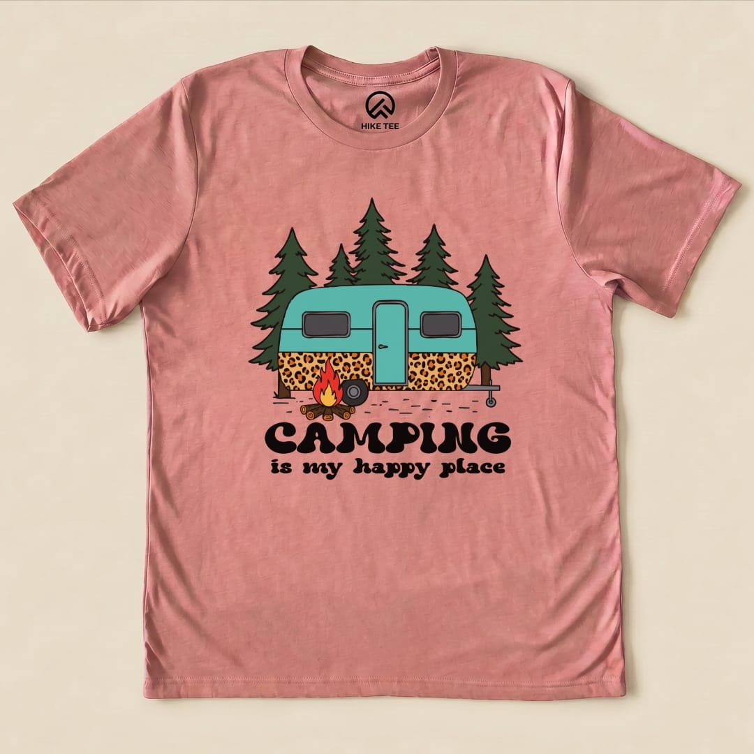 The Camping is My Happy Place Shirt features a whimsical graphic of a teal camper surrounded by trees and a campfire.