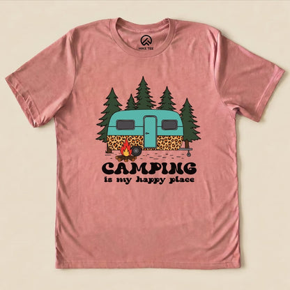 The Camping is My Happy Place Shirt features a whimsical graphic of a teal camper surrounded by trees and a campfire.
