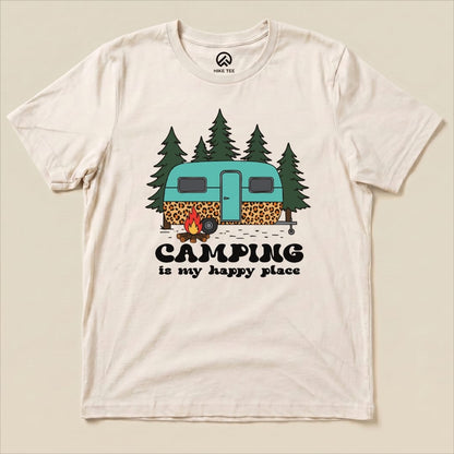 A graphic t-shirt featuring a teal camper surrounded by trees and a campfire, with the slogan "Camping is my happy place.