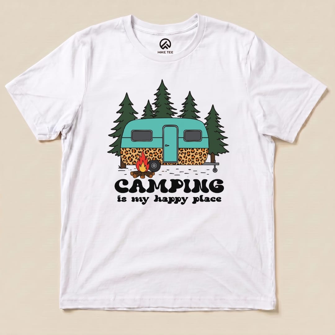 A graphic t-shirt featuring a teal and leopard-print camper surrounded by trees with the slogan "Camping is my happy place.