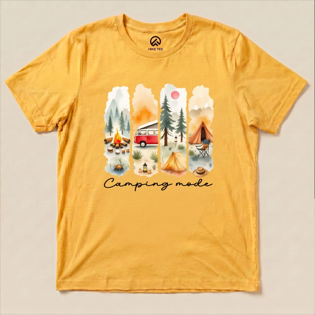 A yellow graphic t-shirt featuring a watercolor design with camping scenes and the phrase "Camping mode" printed below.