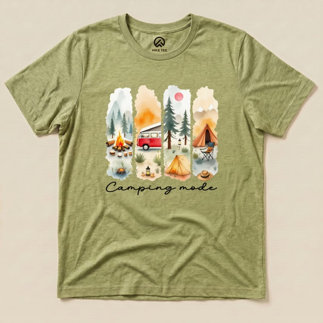 The Camping mode Watercolor Shirt features a vibrant graphic of a camping scene with a vintage van, tents, and a campfire.