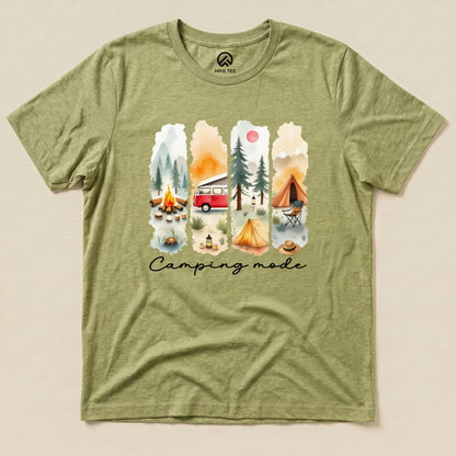The Camping mode Watercolor Shirt features a vibrant graphic of a camping scene with a vintage van, tents, and a campfire.