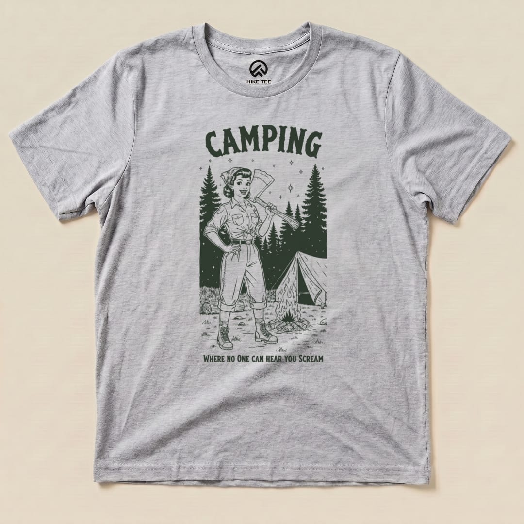 A gray graphic t-shirt featuring a vintage-style illustration of a camper with an axe and the slogan "Camping Where No One Can Hear You Scream.