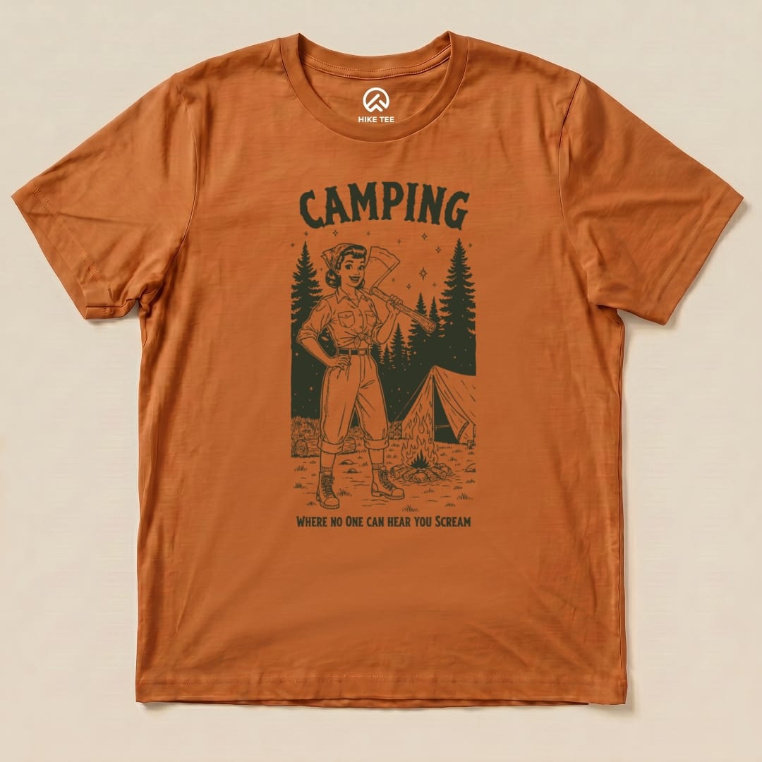 Graphic t-shirt in orange featuring a woman with an axe, surrounded by trees and a tent, with the slogan "Camping No One Hear Shirt.