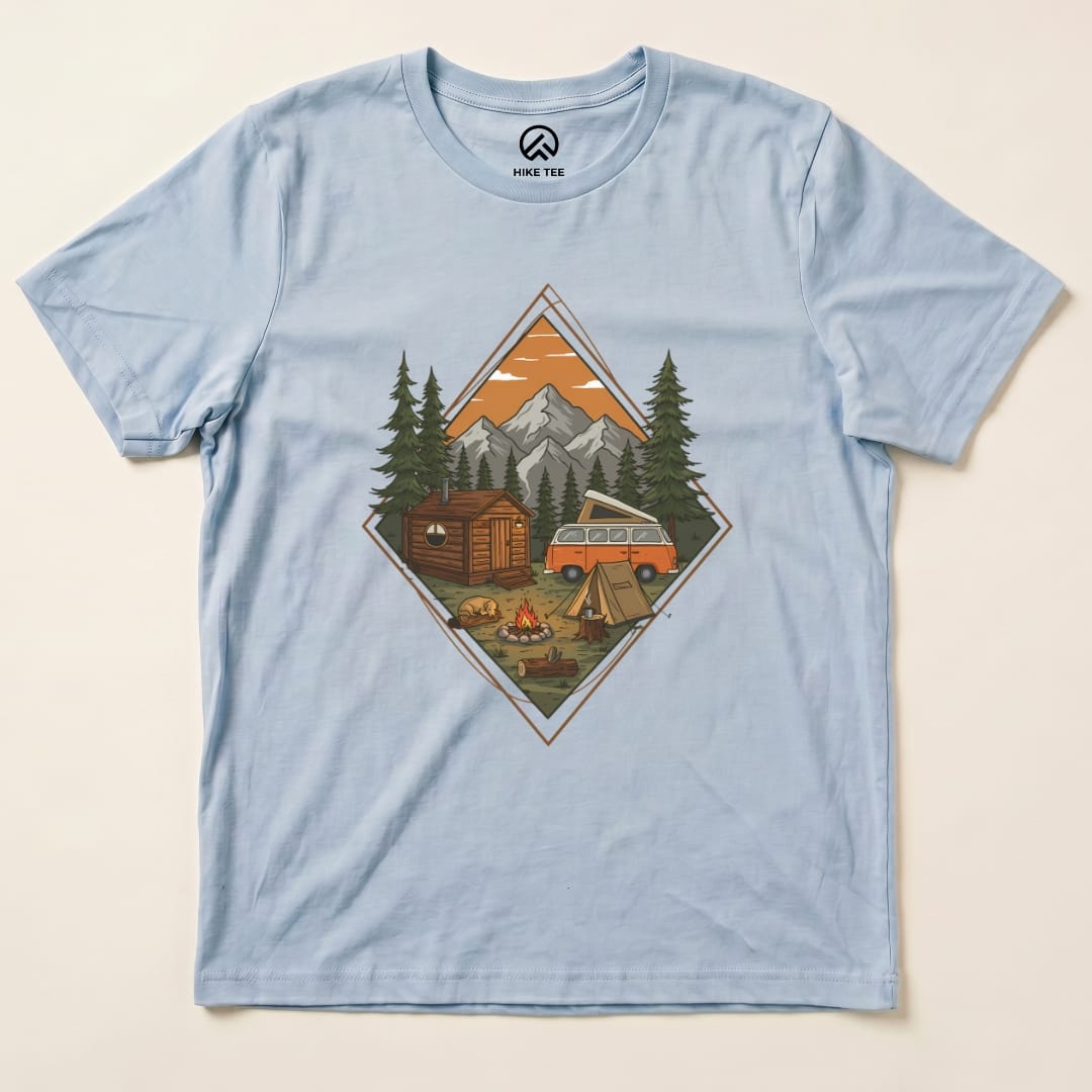A graphic t-shirt featuring a cozy camping scene with a cabin, campfire, and vintage van under a mountain backdrop, labeled "Camping Scenery Shirt.