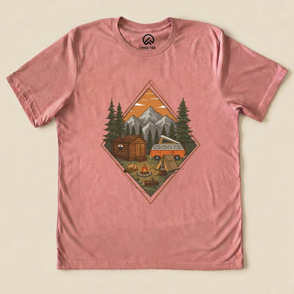 A pink graphic t-shirt featuring a Camping Scenery Shirt design with a cabin, campfire, tent, and vintage van against a mountain backdrop.