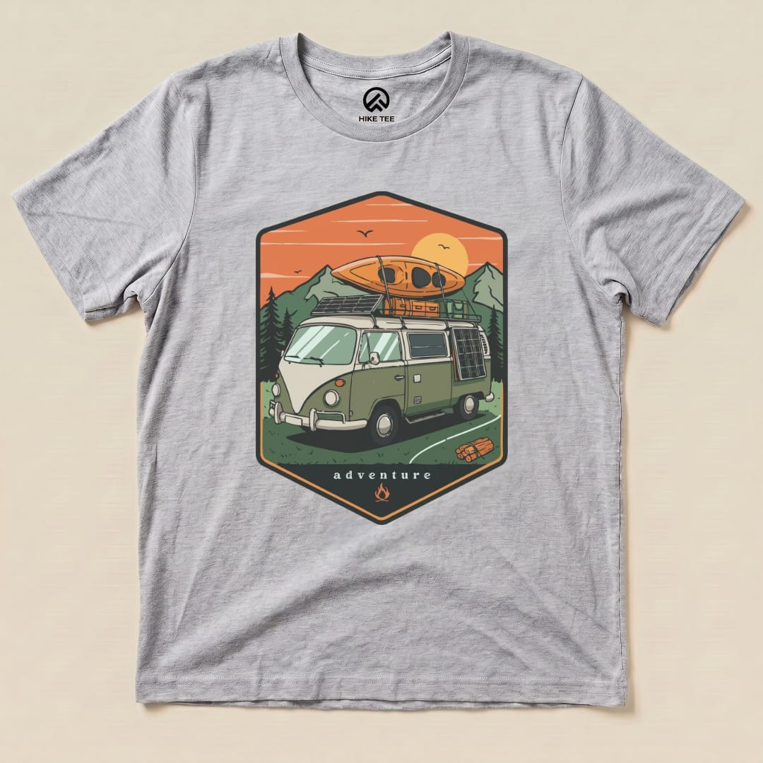 A graphic t-shirt featuring a green camping van with a kayak on top and the word "adventure" below, titled "Camping Van Adventure Shirt.