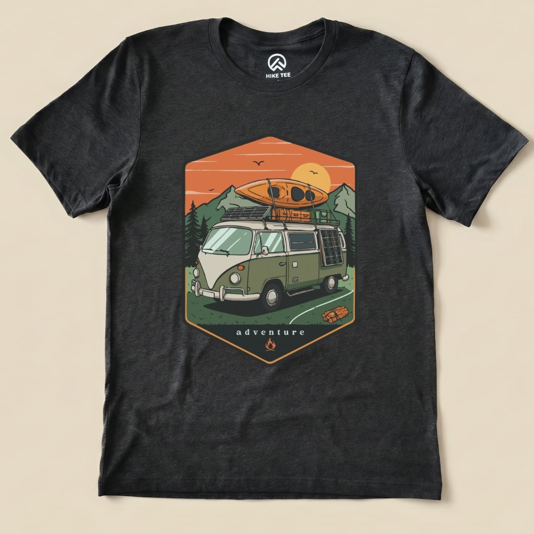 A graphic t-shirt featuring a vintage camping van with a kayak on top and the word "adventure" displayed below.