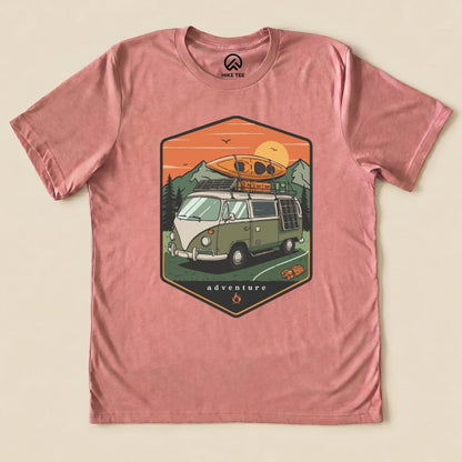 A graphic t-shirt featuring a vintage camping van with a kayak on top, surrounded by mountains and the word "adventure.