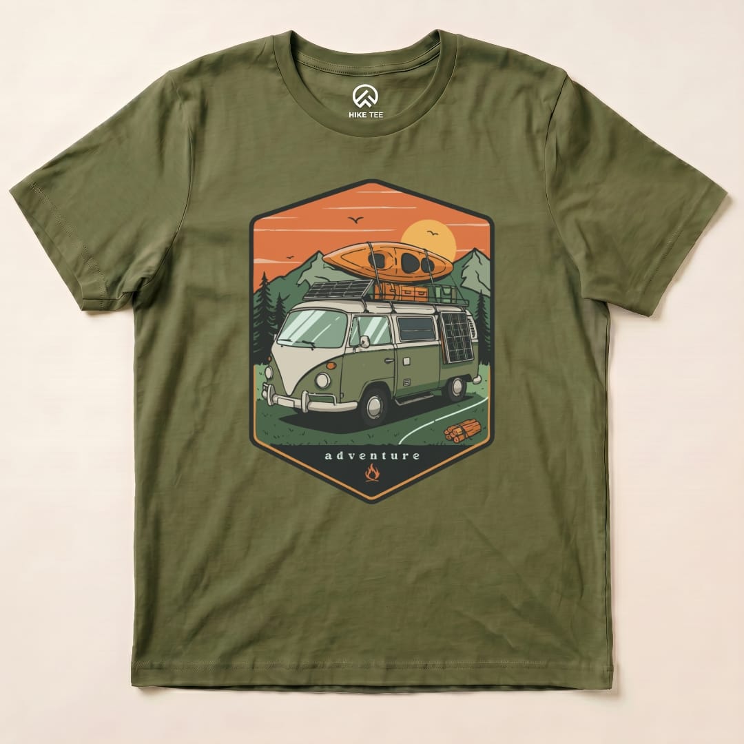 The graphic t-shirt displays a vintage camping van with a kayak on top and mountains in the background, featuring the words "adventure.