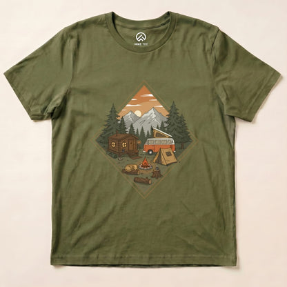 A graphic t-shirt in an olive green hue featuring a camping scene with a retro van, cabin, mountains, and a campfire, labeled "Camping Vibes Shirt".