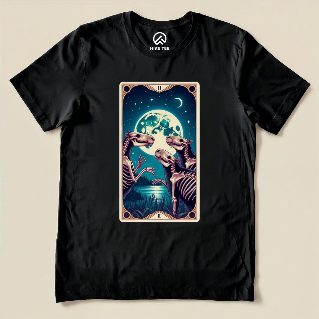 The Capybara Moon Tarot Card Shirt features a whimsical illustration of two capybaras in a tarot card design under a full moon.