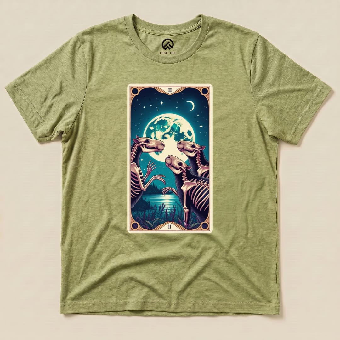 The Capybara Moon Tarot Card Shirt features a vibrant graphic of skeletons in a mystical night scene with a large moon.