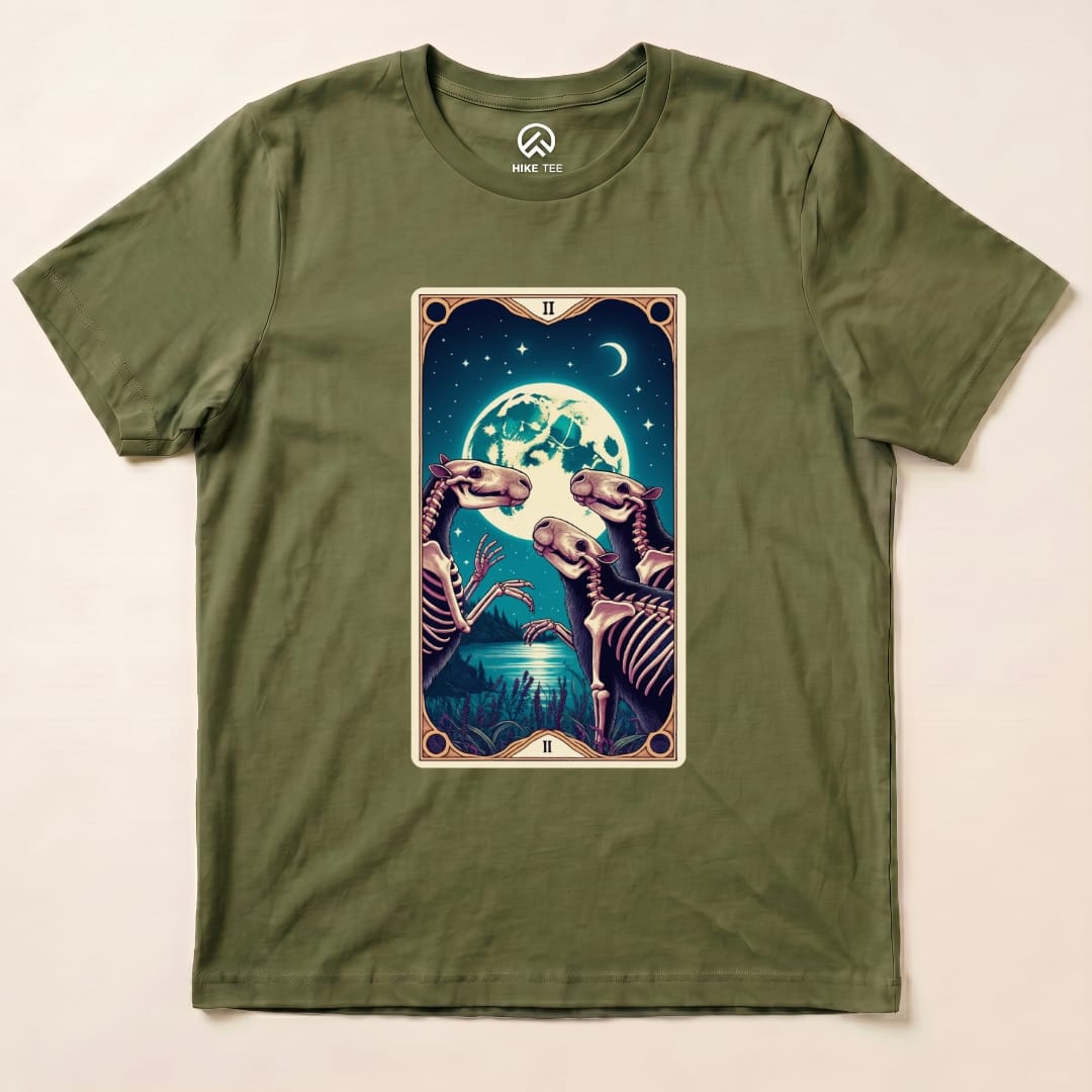 The Capybara Moon Tarot Card Shirt features a vibrant graphic of skeletal capybaras under a full moon, set against a rich green background.