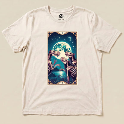 A graphic t-shirt featuring a whimsical design of skeletal capybaras and a full moon, titled "Capybara Moon Tarot Card Shirt.