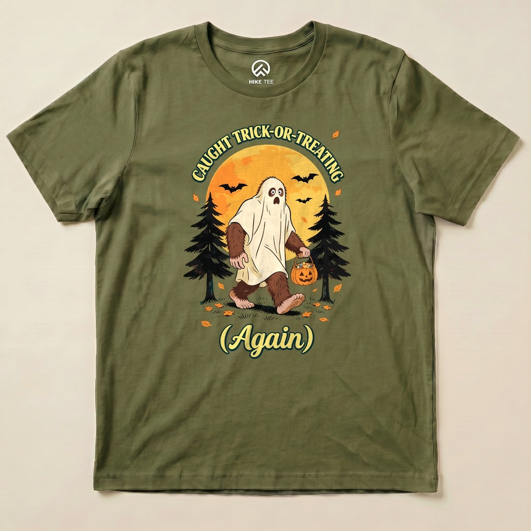 Military Green Caught Trick-or-Treating Again Shirt with a Bigfoot in a ghost sheet trick-or-treating graphic