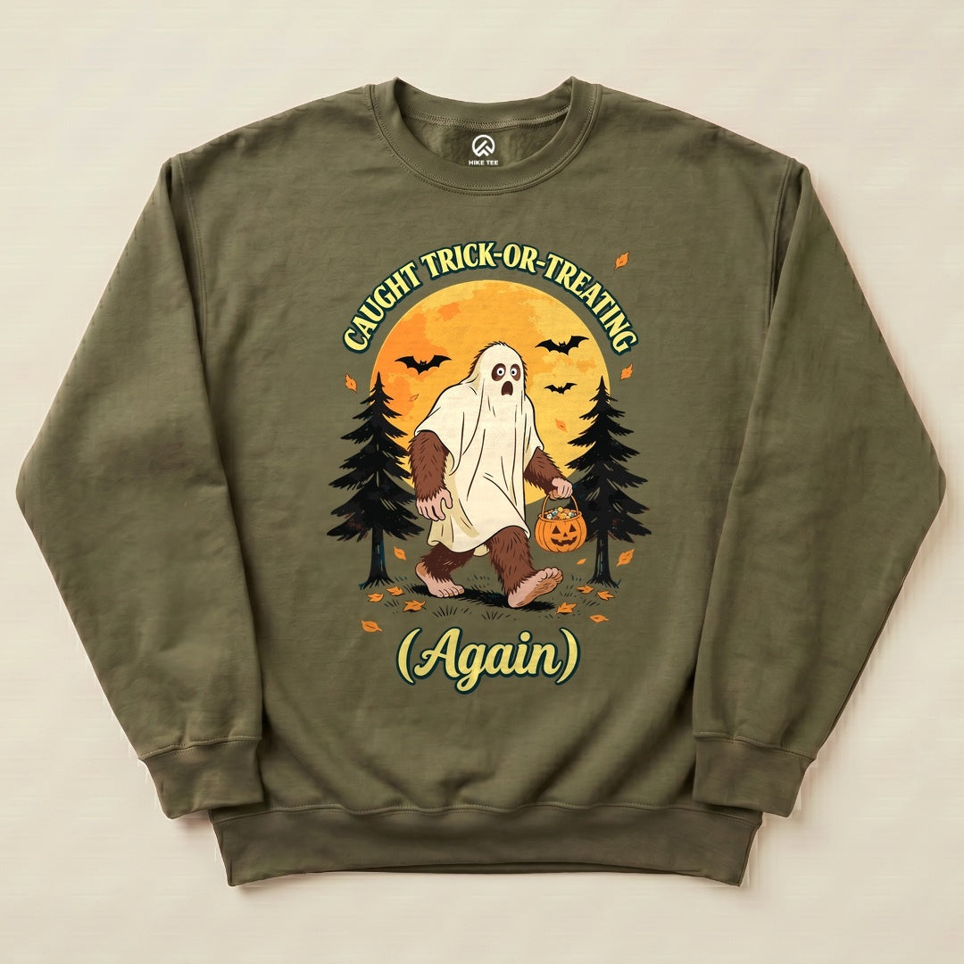 The "Caught Trick-or-Treating Again Sweatshirt" features a bigfoot in a ghost costume, holding a pumpkin, surrounded by trees and bats.