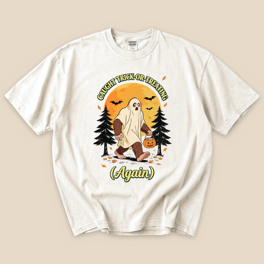 Ivory Caught Trick-or-Treating Again T-Shirt with a Bigfoot in a ghost sheet trick-or-treating graphic