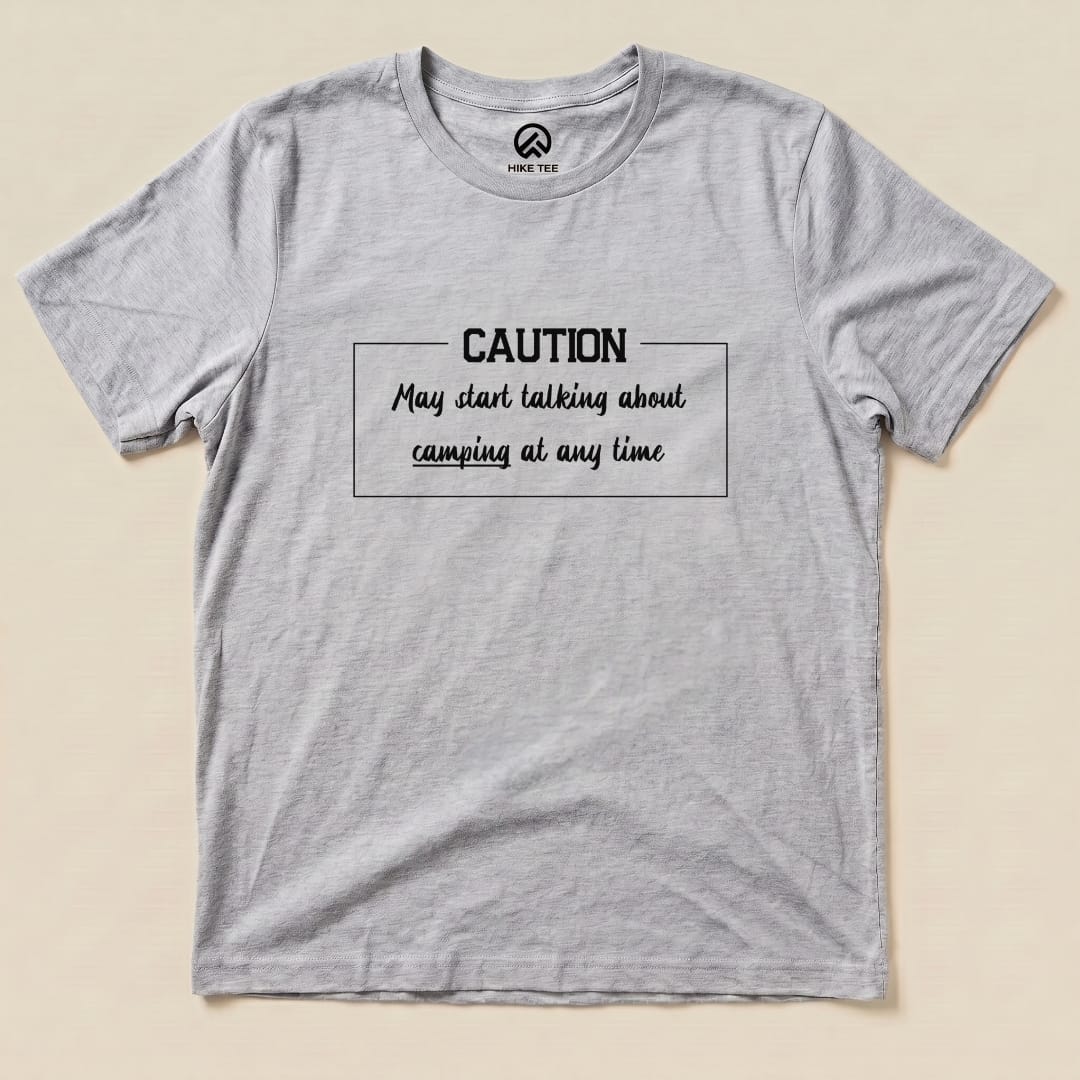 A gray graphic t-shirt featuring the text "Caution May start talking about camping at any time" in a casual font.