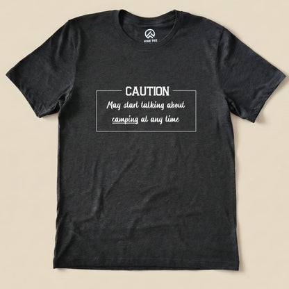 Graphic t-shirt in dark gray featuring the text "Caution May start talking about camping at any time" in a playful font.